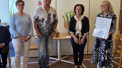 Fyra personer står vid ett bord. En håller i en tvla.