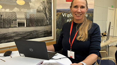 Leende kvinna med ljus hår i hästsvans vid en dator