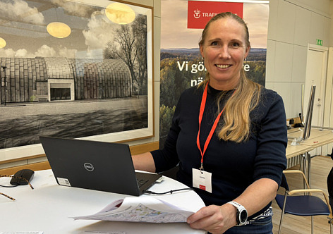 Leende kvinna med ljus hår i hästsvans vid en dator