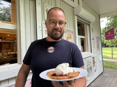Dan Ström håller upp en våffla med grädde, sylt och glass