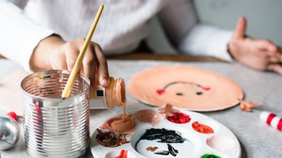 närbild av palett med målarfärger och hand med pensel