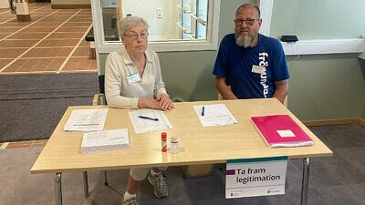 Två röstmottagare i stadshuset bakom ett bord