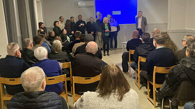 Ryggar på många personer i en sal- Flera personer framifrån längst bak i bilden.
