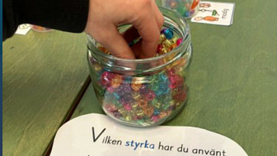 En barnhand plocka färgglada pärlor ur en burk