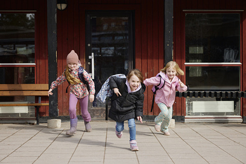 tre lågstadiebarn springer på skolgård
