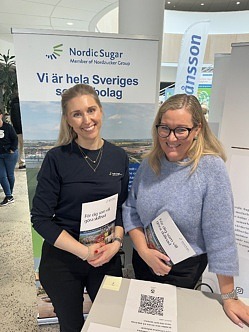 Två medarbetare från nordic sugar står vid ett monter bord