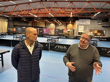 Två man samtalar i en bordtennishall