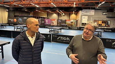 Två man samtalar i en bordtennishall