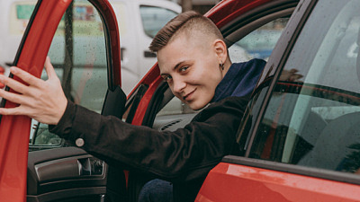 Ung glad man tittar ut genom öppen bildörr