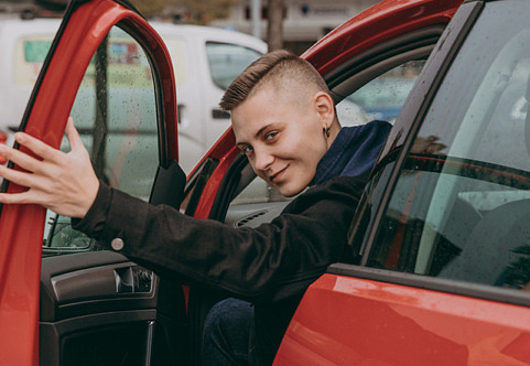Ung glad man tittar ut genom öppen bildörr