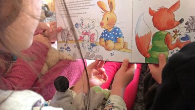 Barn tittar i en bok tillsammans med pedagog.