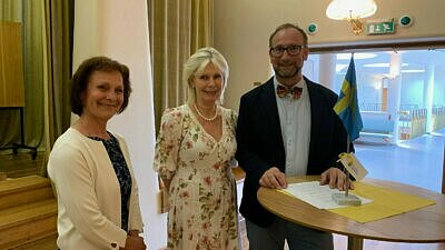 Två kvinnor och en man framför ett bord