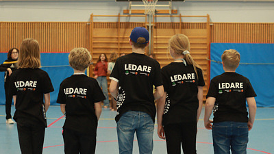 Fem unga i svarta t-shirts där det står Ledare i vitt på ryggen