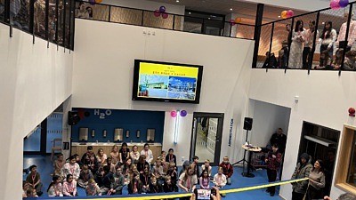 Inomhus miljö salleruppskolan, barn klipper av invigningsband. elever och lärare samlade runt