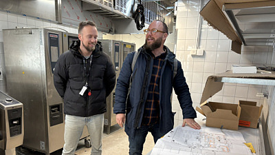 Två män tittar på ritningar i ett kök som håller på att byggas om