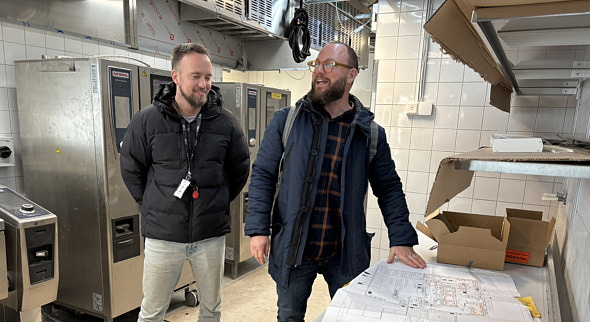 Två män tittar på ritningar i ett kök som håller på att byggas om