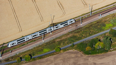 Tåg körandes på räls i Skåne. åkrar vid sidan om