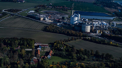 Flygbild över hus, åkrar och en fabrik